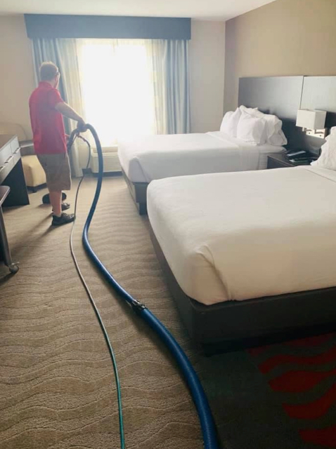 Professional Carpet Cleaning employee cleaning a hotel room carpet