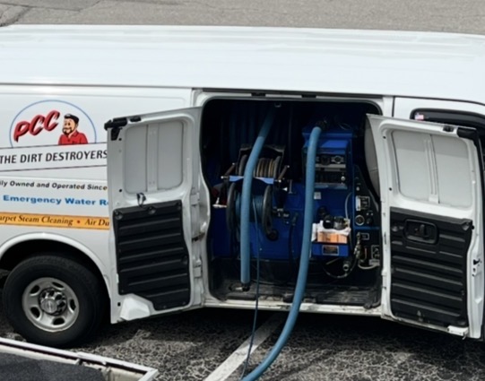 Professional carpet cleaning truck with doors open and hoses running out